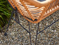 Chaise en osier avec cadre en métal noir sur du gravier.