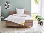 Une couette blanche Paleis sur un lit avec une tête de lit beige.