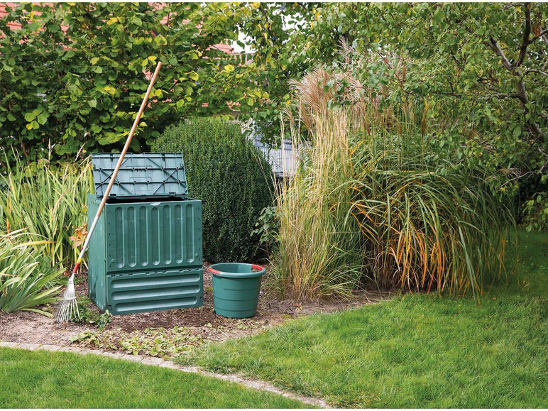 Compost, seau et râteau dans un jardin.