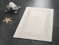 Tapis de bain avec bordure décorative et serviettes sur une balance.
