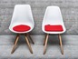 Deux chaises blanches avec des coussins rouges.