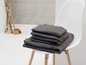 Une pile de serviettes de couleur gris foncé sur une chaise blanche
