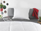 Une couette et un oreiller blancs sur un lit gris