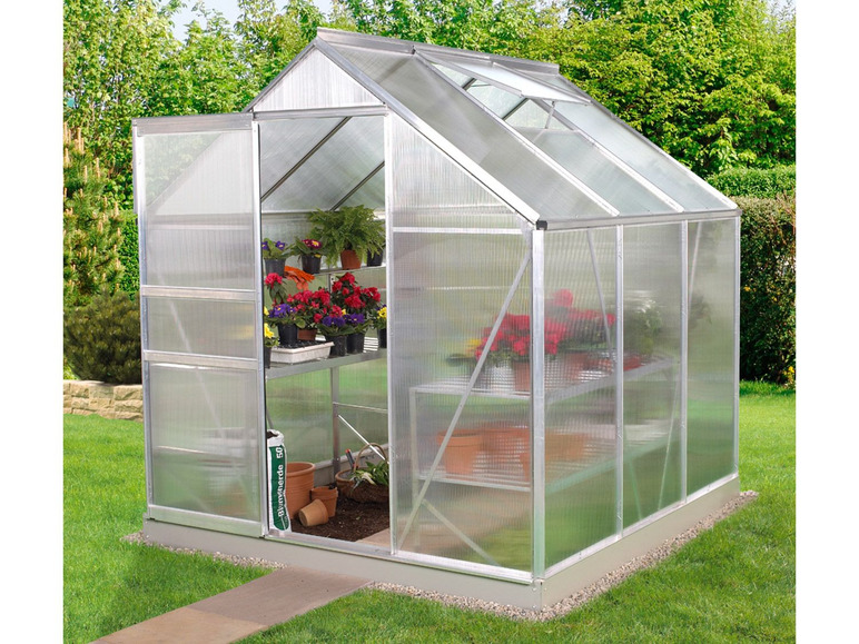 Une petite serre avec un toit et des côtés transparents, contenant des fleurs et des plantes.