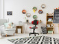 Une chambre d'enfant avec un fauteuil de bureau rouge, un fauteuil gris et un tapis noir et blanc.