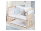 Un lit bébé en bois avec un matelas, un oreiller et un motif d'étoiles.