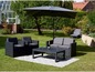 Un salon de jardin noir avec un parasol sur la pelouse.