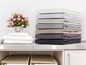 Une pile de draps de lit de différentes couleurs.