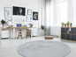 Un tapis rond gris dans une pièce claire avec un bureau, des chaises et une bibliothèque.