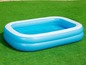 Une piscine gonflable bleue avec de l'eau sur l'herbe.