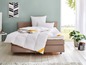 Une couette blanche Relate sur un lit avec une tête de lit beige