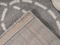 Détail d'un tapis gris avec un motif blanc, le bord est visible.