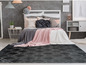Un tapis gris avec un motif en losanges devant un lit avec des couvertures roses et grises.