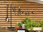 Outils de jardin, dont une pelle, un râteau, des cisailles et un arrosoir, suspendus à une clôture en bois.