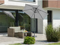 Un parasol gris sur une terrasse avec un salon de jardin.
