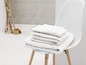 Pile de serviettes blanches sur une chaise blanche.