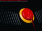 Un bouton rouge avec un bord jaune sur un fond noir.