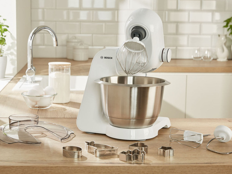 Un robot pâtissier Bosch blanc avec un bol, un fouet et des emporte-pièces.