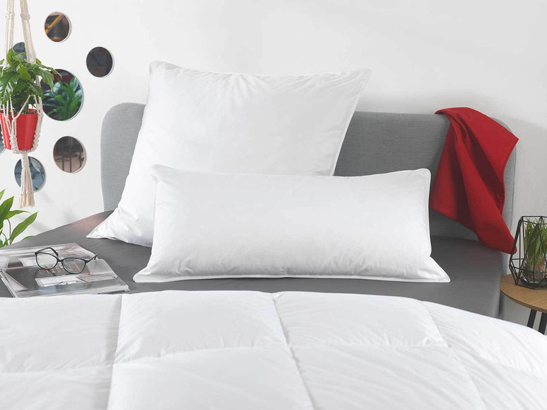 Couette et oreillers blancs sur un lit gris.