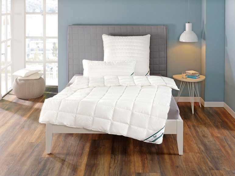 Une couette et des oreillers blancs sur un lit dans une chambre.