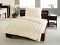 Une couette beige de la marque Sanwald sur un lit en bois.