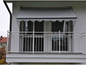 Un balcon avec un store rayé et une balustrade blanche.