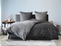 Un lit avec des draps gris à pois et à rayures.
