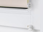 Un store plissé beige avec un mécanisme blanc sur une fenêtre.