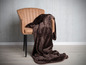 Une couverture marron sur un fauteuil en cuir.