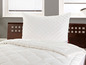Couette et oreiller blancs sur un lit en bois.