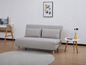 Un canapé-lit gris avec des pieds en bois et des coussins dans un salon moderne.
