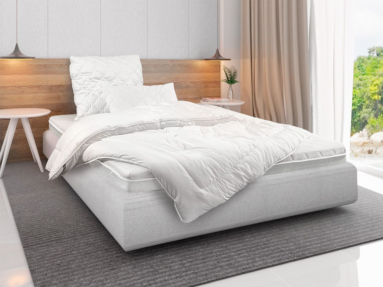 Une couette, un oreiller et un matelas blancs sur un lit dans une chambre à coucher.