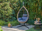 Un fauteuil suspendu avec un cadre en bois dans un jardin avec des plantes vertes.