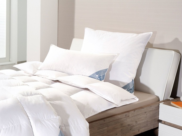 Une couette blanche et des oreillers sur un lit en bois.