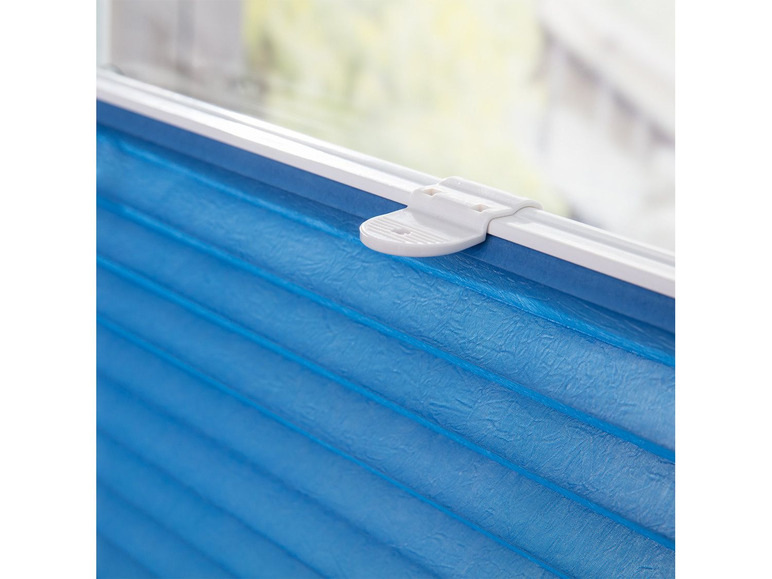 Un store plissé bleu monté sur une fenêtre