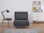 Un canapé-lit gris dans un intérieur moderne avec un tapis, une table d'appoint et une commode.