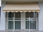 Un store rayé au-dessus d'un balcon avec une balustrade blanche.