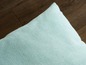 Un coussin bleu clair sur un sol en bois.