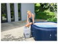 Une femme à côté d'un jacuzzi gonflable Lay-Z-Spa avec une pompe incluse.