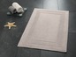 Tapis de bain beige avec bordure décorative, deux serviettes et une étoile.