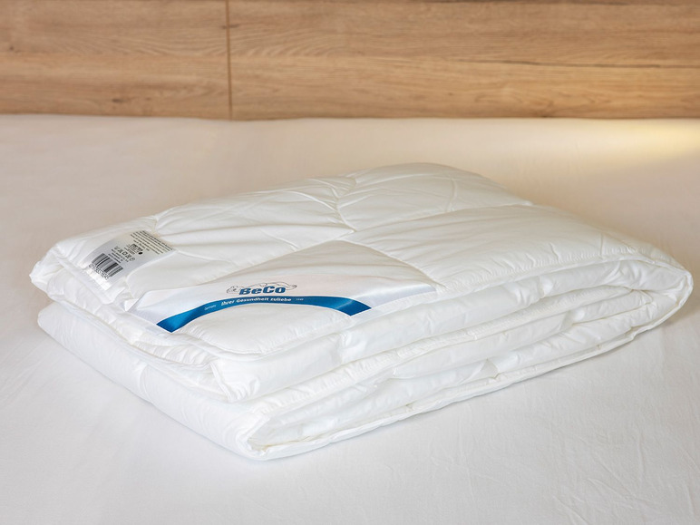 Une couette blanche BeCo sur des draps blancs.