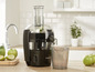 Un extracteur de jus Philips avec un pichet en verre, qui verse du jus dans un verre en verre.