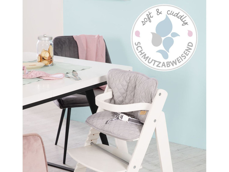Une chaise haute blanche avec un siège rembourré gris.
