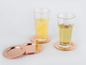 Deux verres avec des boissons sur des sous-verres en cuivre.