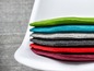 Ensemble de coussins en feutre colorés empilés sur une chaise blanche.