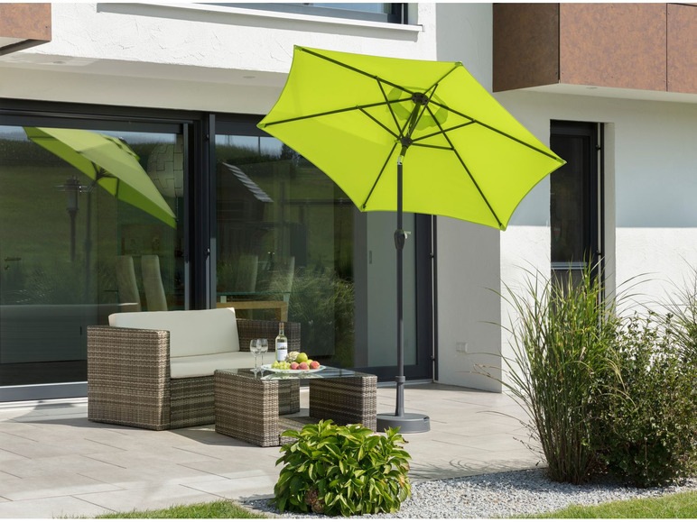 Un parasol vert sur une terrasse avec un salon de jardin.
