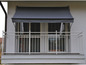 Un balcon avec une marquise grise et une balustrade blanche.