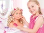 Une petite fille joue avec une poupée et utilise du maquillage et des accessoires pour cheveux.