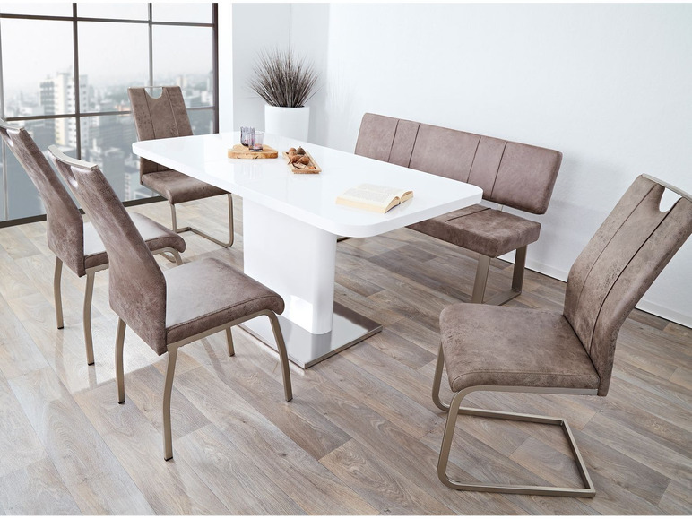 Une table à manger blanche avec des chaises et un banc bruns.