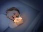 Un enfant tient une veilleuse en forme de nuage qui brille.
